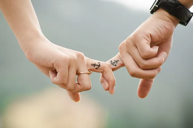 valentines day background, couple, hands, tattoos, fingers, intertwined, anchor tattoos, lovers, together, touch, relationship, closeup. Aftercare handouts for Phoenix, Miami and Minneapolis, climate by climate