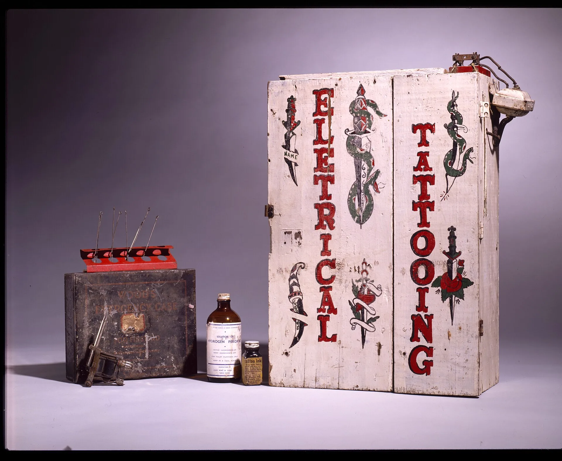 Unidentified (American), Eletrical Tattooing, ca. 1920s-1930s, painted wood with iron and brass trim and electrical fittings, tattooing needles and ink, paper card, labels, metal box, and glass bottles, Smithsonian American Art Museum, Gift of Herbert Waide Hemphill, Jr. and museum purchase made pos. Notes on tattoo studio expansion from the field
